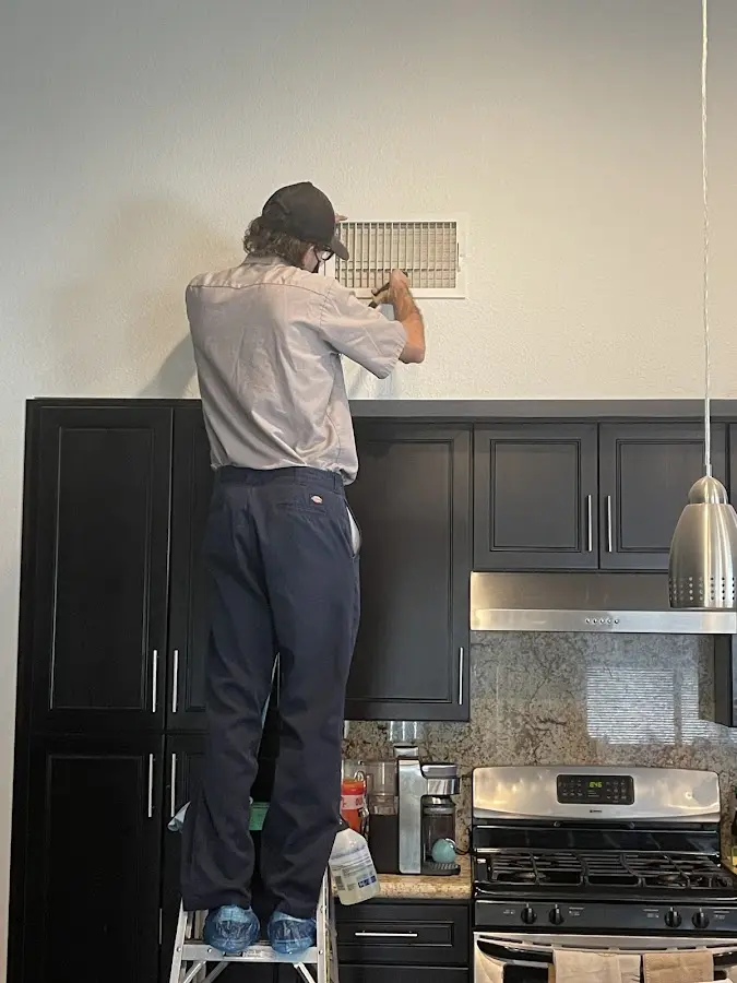 Technician inspecting an air vent during HVAC service in Rossville